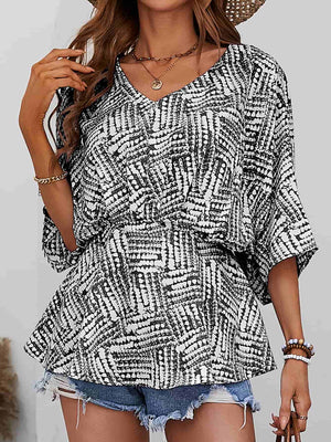 Black and white abstract print cinched waist blouse with V-neck and short sleeves.