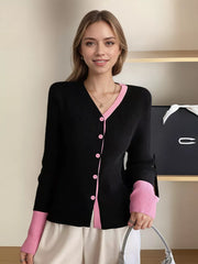 Black ribbed cardigan with pink contrast trim and buttons, long sleeves.