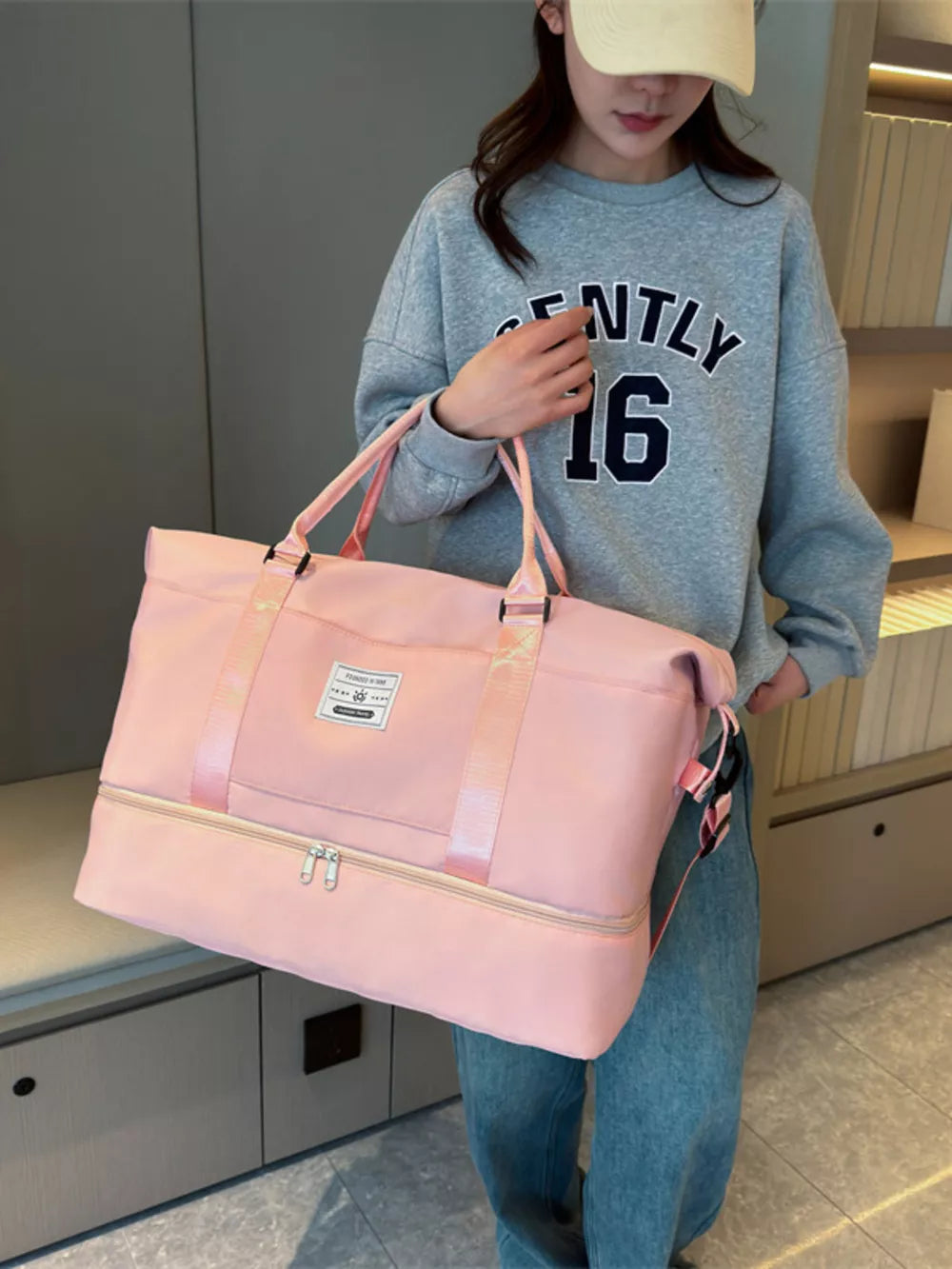 Light pink duffel bag with zippered bottom compartment and dual handles.