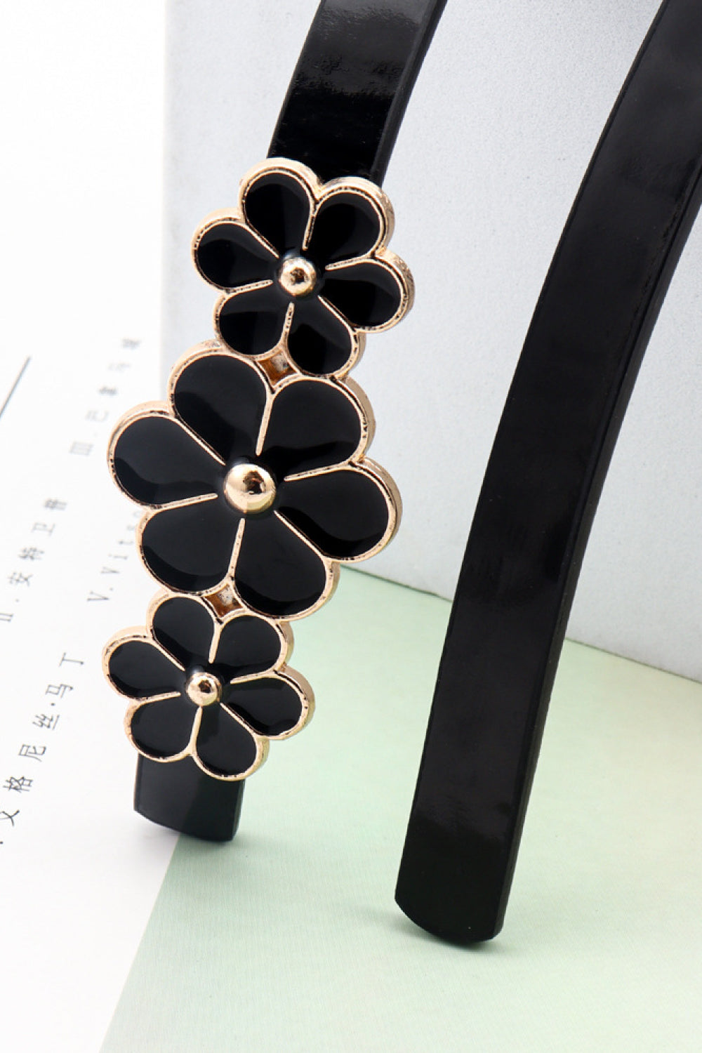 Black skinny belt with gold trim and black floral blossom embellishments.