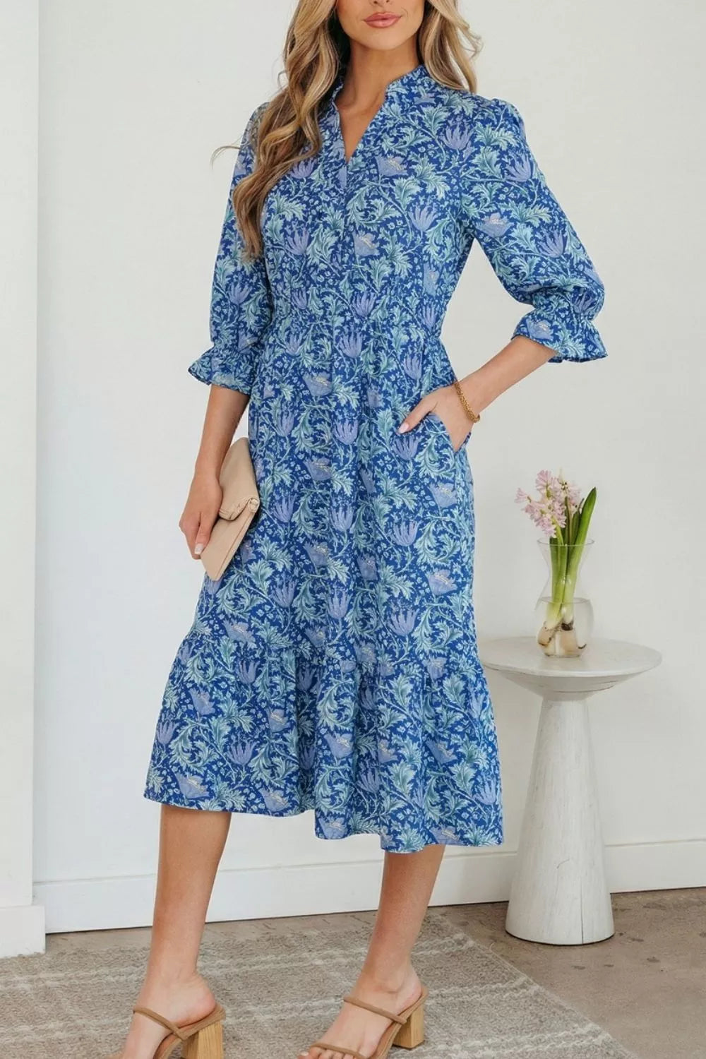 Blue floral cotton midi dress with cinched waist and frilled cuffs.