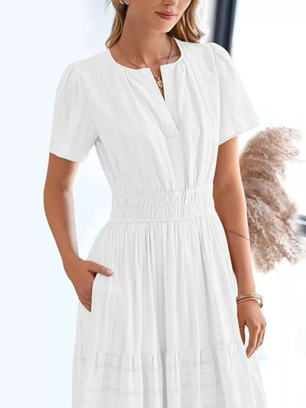 White tiered midi dress with V-neck, short sleeves, smocked waist, and pockets.