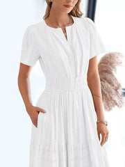 White tiered midi dress with V-neck, short sleeves, smocked waist, and pockets.