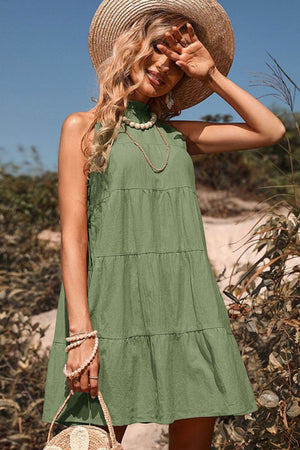 Matcha green halter neckline tiered mini dress with a bow-back detail.