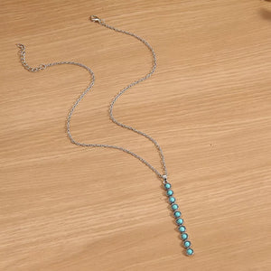 Delicate silver necklace with a vertical pendant of pastel blue beaded accents.