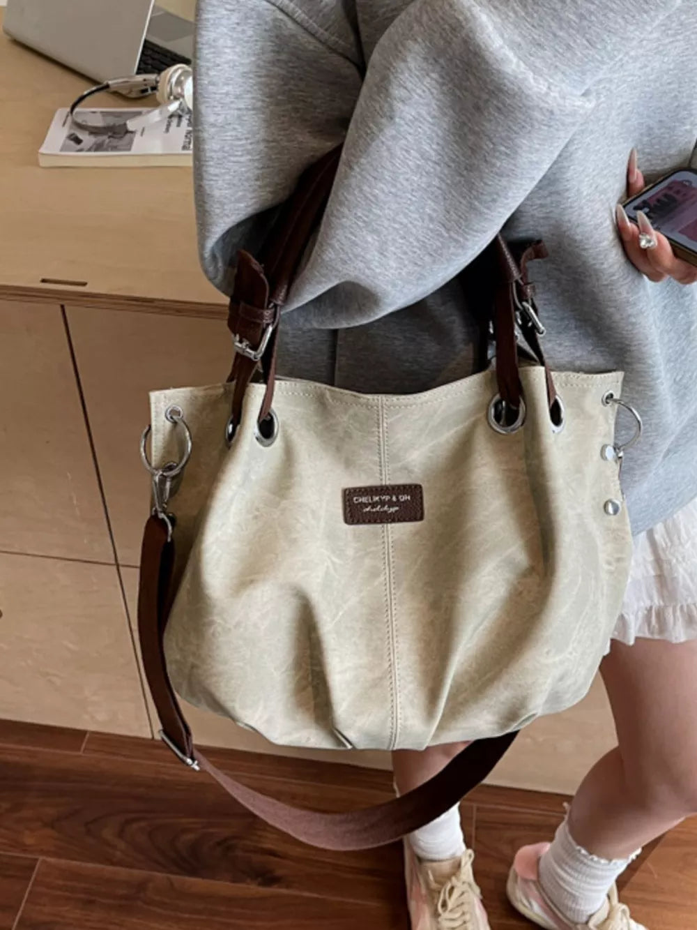 Off-white slouchy crossbody bag with brown straps and silver hardware.