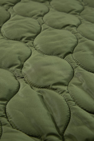 Moss green quilted sleeveless jacket detail showing diamond stitching pattern