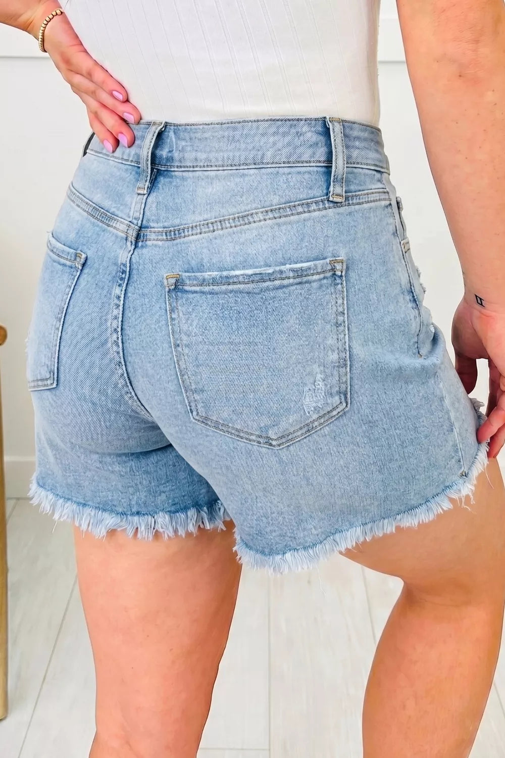 Light wash denim shorts with raw hem and distressed details.