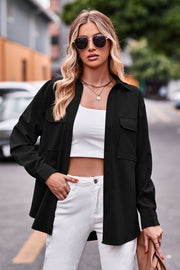 Black oversized utility shirt with chest pockets and button front, styled with white jeans.