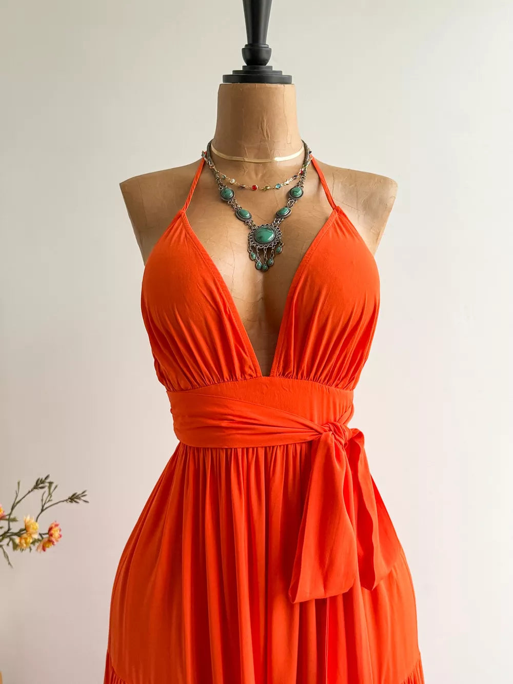 Orange tiered maxi dress with plunging V-neck, halter straps, and cinched waist tie.