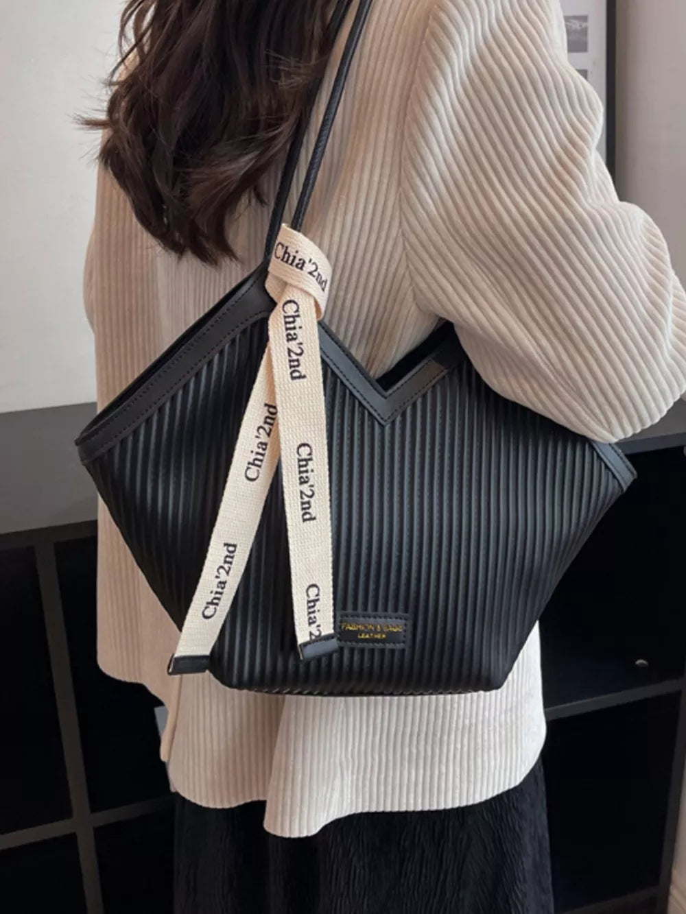 Black ribbed texture large shoulder bag with decorative ribbon detail.