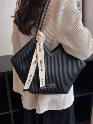 Black ribbed texture large shoulder bag with decorative ribbon detail.