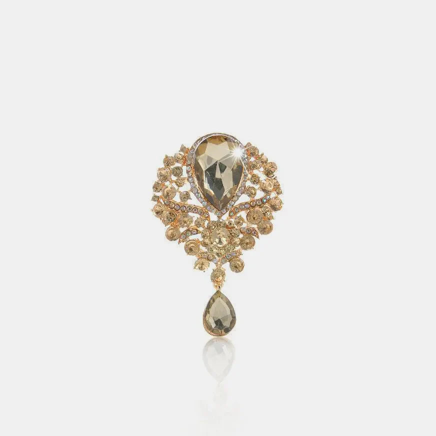 Regal teardrop embellished brooch in champagne with intricate gold alloy details.