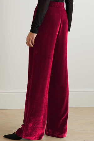 Burgundy velvet palazzo trousers with high waist and wide leg, styled with black pointed shoes.