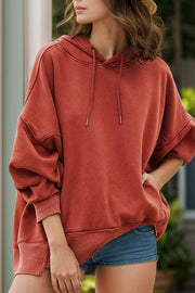 Oversized rust washed cotton hoodie with drawstring hood and cuffed sleeves.