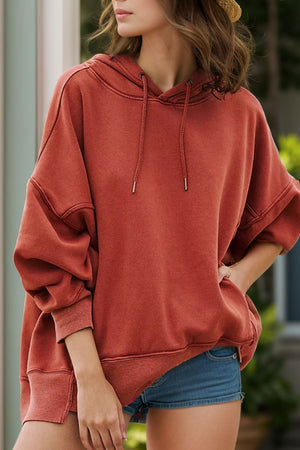 Oversized rust washed cotton hoodie with drawstring hood and cuffed sleeves.