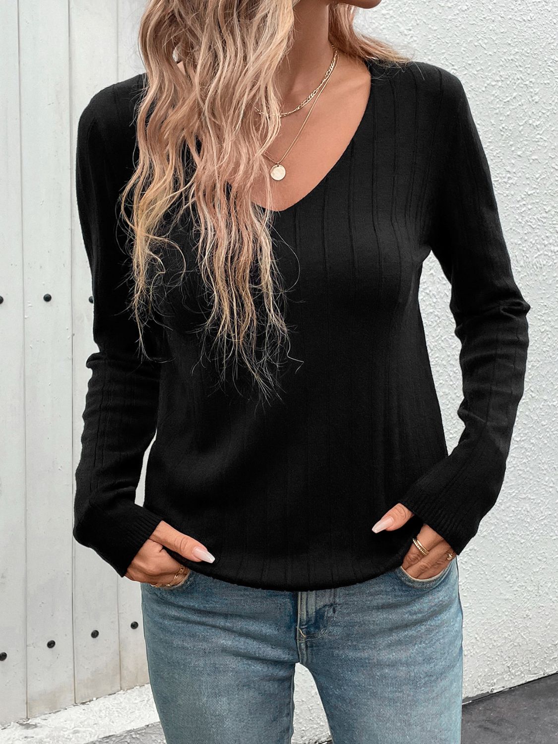Black ribbed V-neck sweater with long sleeves and a relaxed fit.