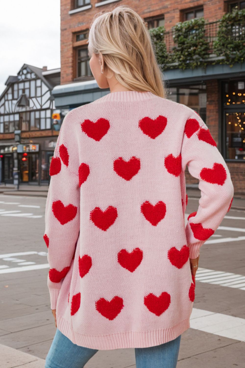 Pink acrylic knit cardigan with allover red heart appliqué and button front.