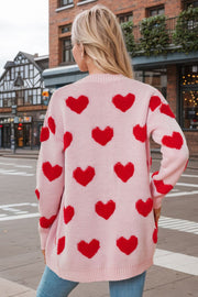 Pink acrylic knit cardigan with allover red heart appliqué and button front.