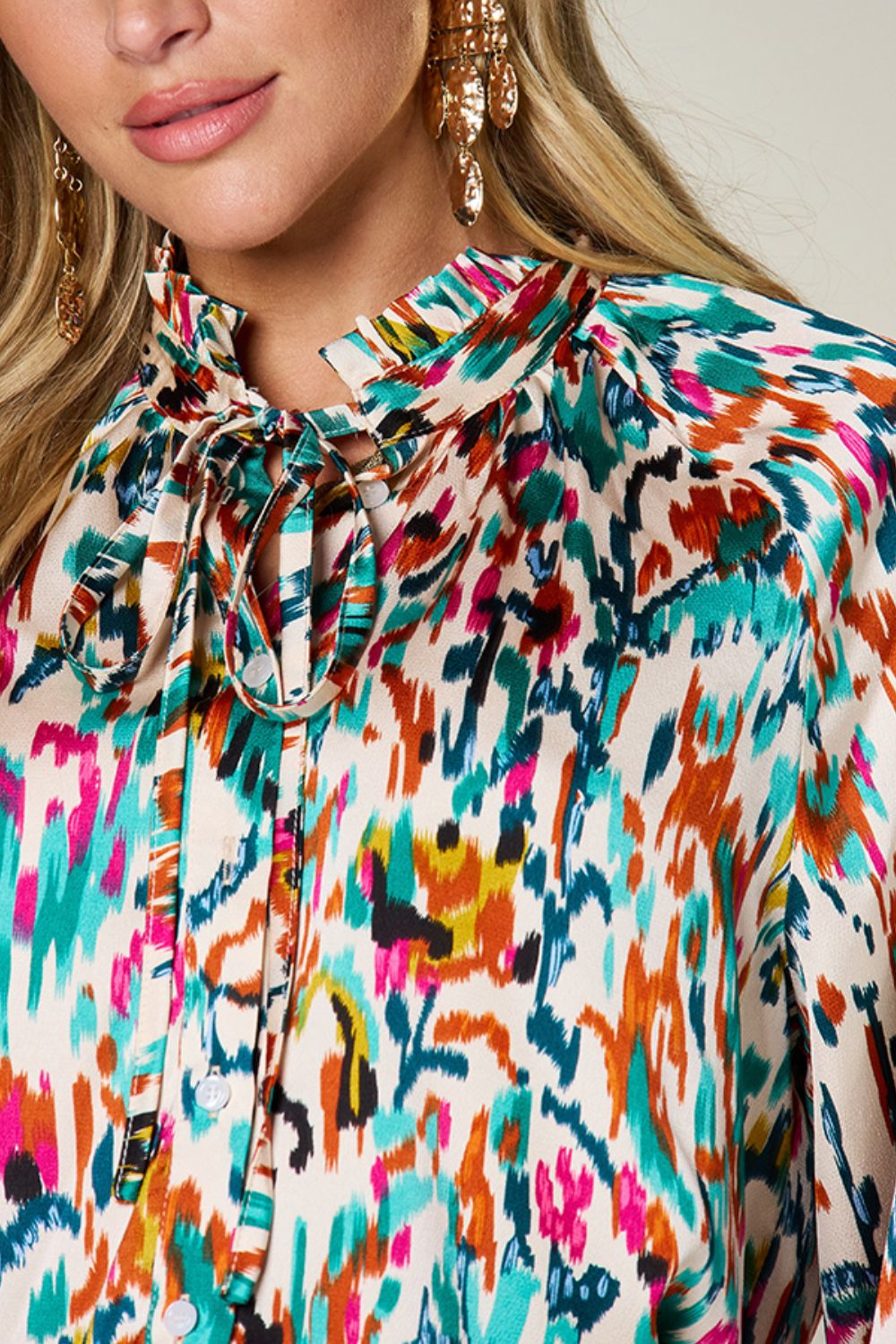 Silk tie-neck blouse with abstract ikat print and button closure.
