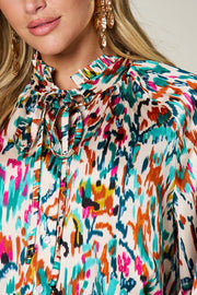 Silk tie-neck blouse with abstract ikat print and button closure.