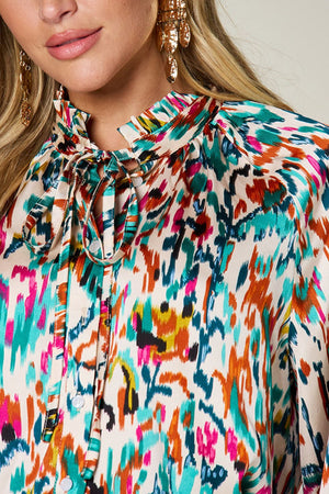 Silk tie-neck blouse with abstract ikat print and button closure.