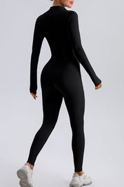 Black zip-front bodycon jumpsuit with long sleeves and thumbholes, worn with sneakers