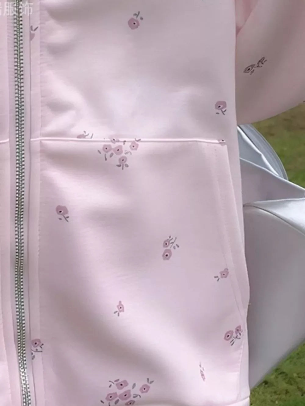 Pink floral zip-up sweatshirt with a chest pocket and subtle floral pattern.
