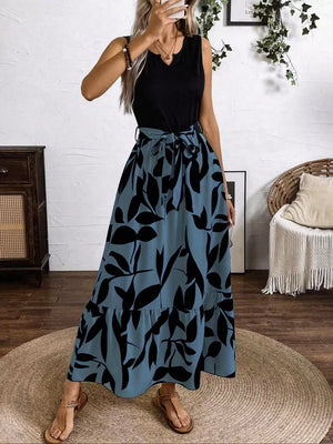 Maxi dress with black leaf print on blue grey, belted waist, tiered hem, and V-neck.
