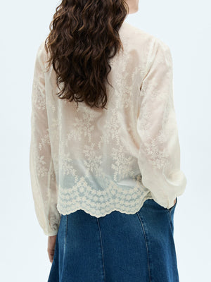 Sheer apricot blouse with floral embroidery and scalloped hem.