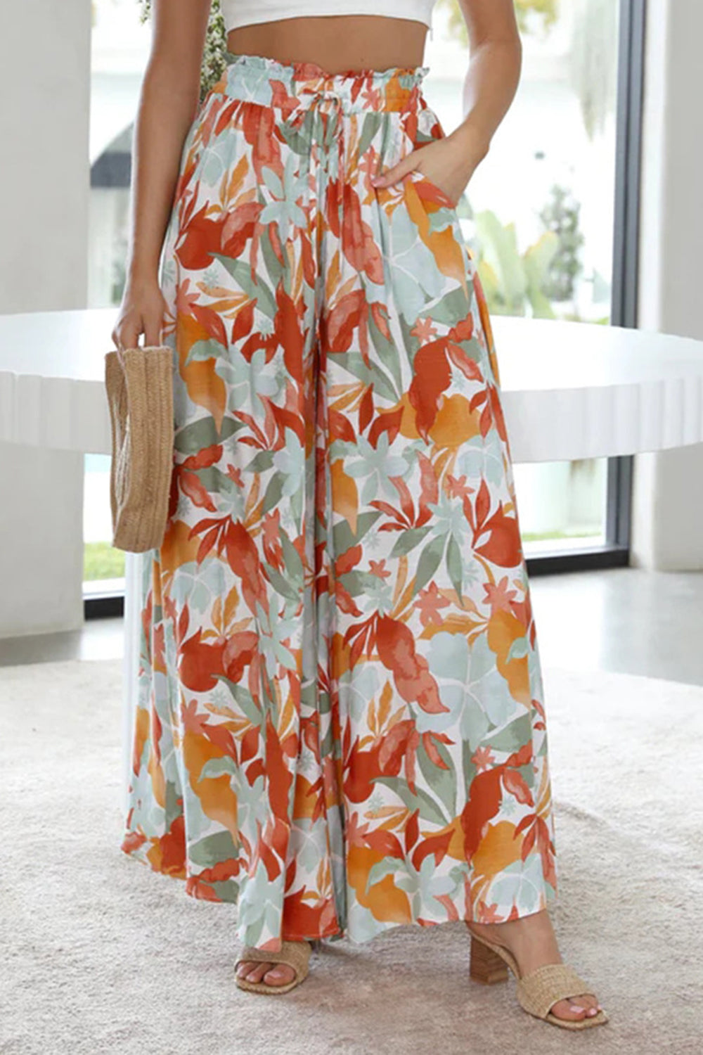 Botanical print palazzo trousers with paperbag waist and wide legs in orange, green, and aqua.