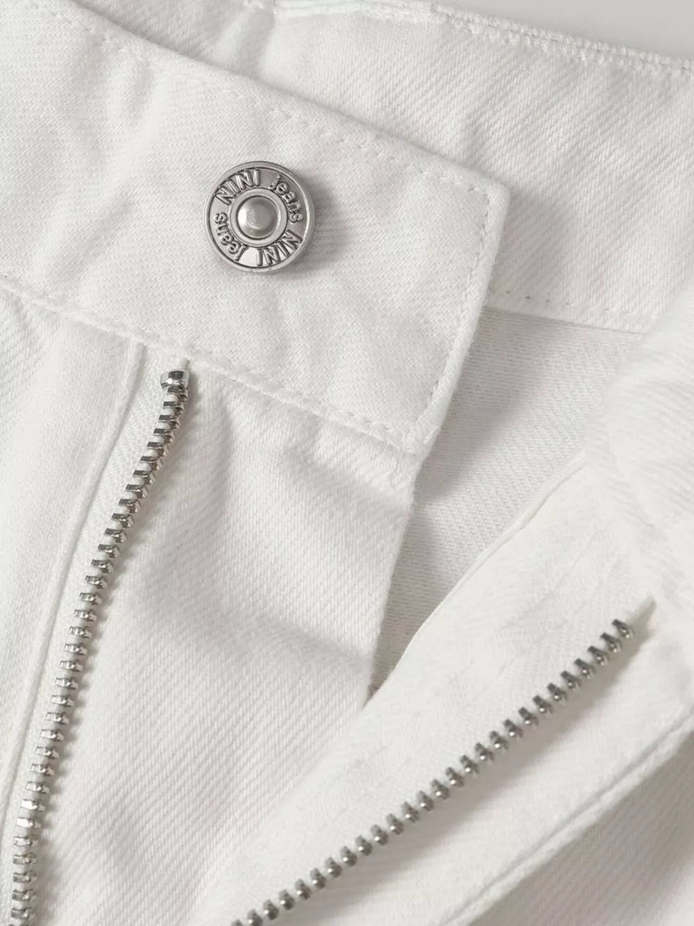 White relaxed fit wide leg sweatpants with silver button and zipper detail.