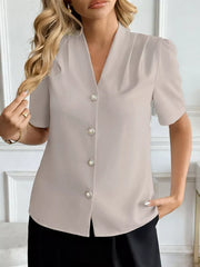 Apricot V-neck short sleeve shirt with pearl buttons and subtle shoulder pleats.