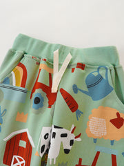 Light green cotton toddler shorts with farm animal print, rainbow, tractor, and watering can.