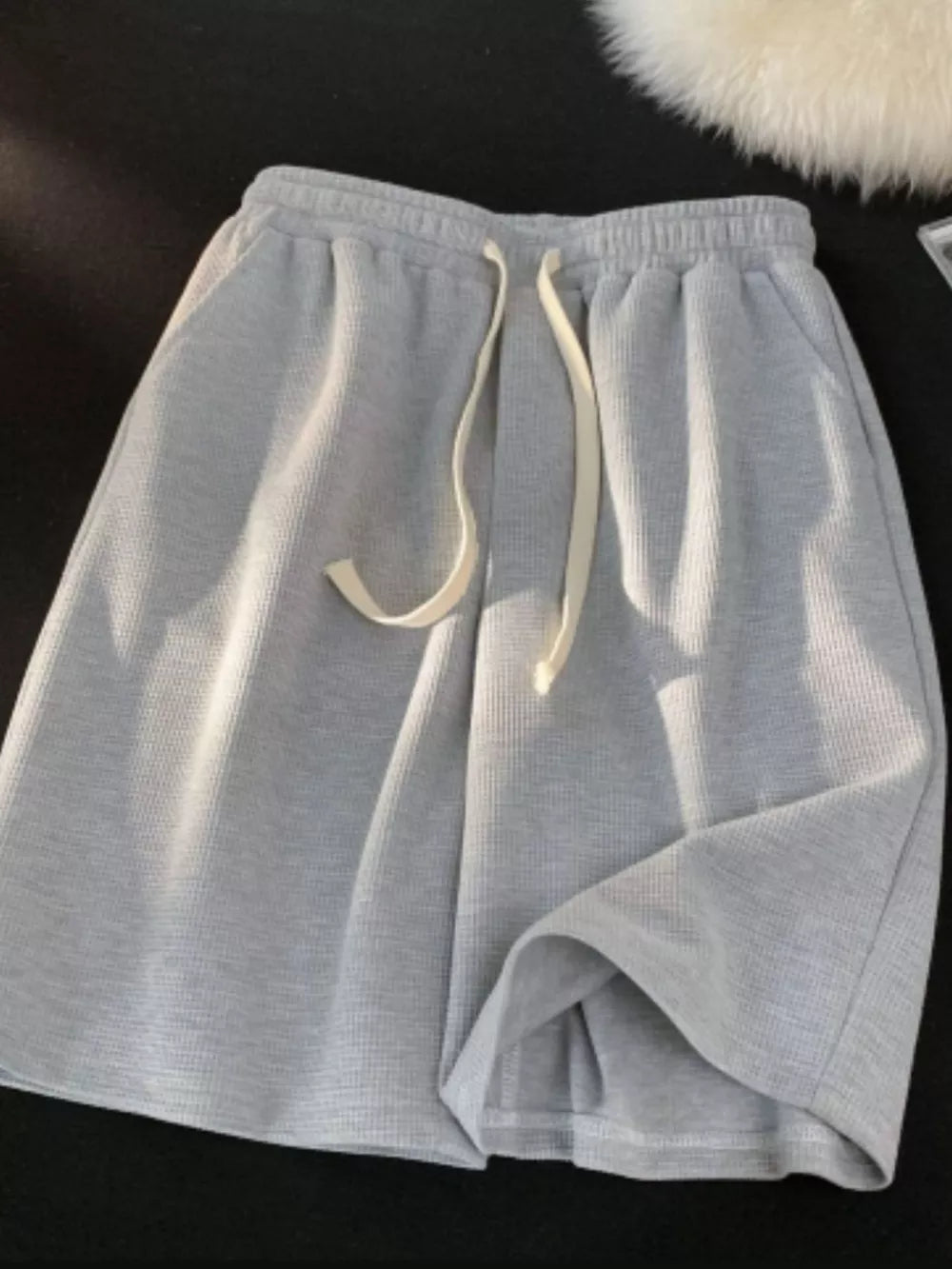 Grey waffle knit boxer shorts with a drawstring waist and pockets.