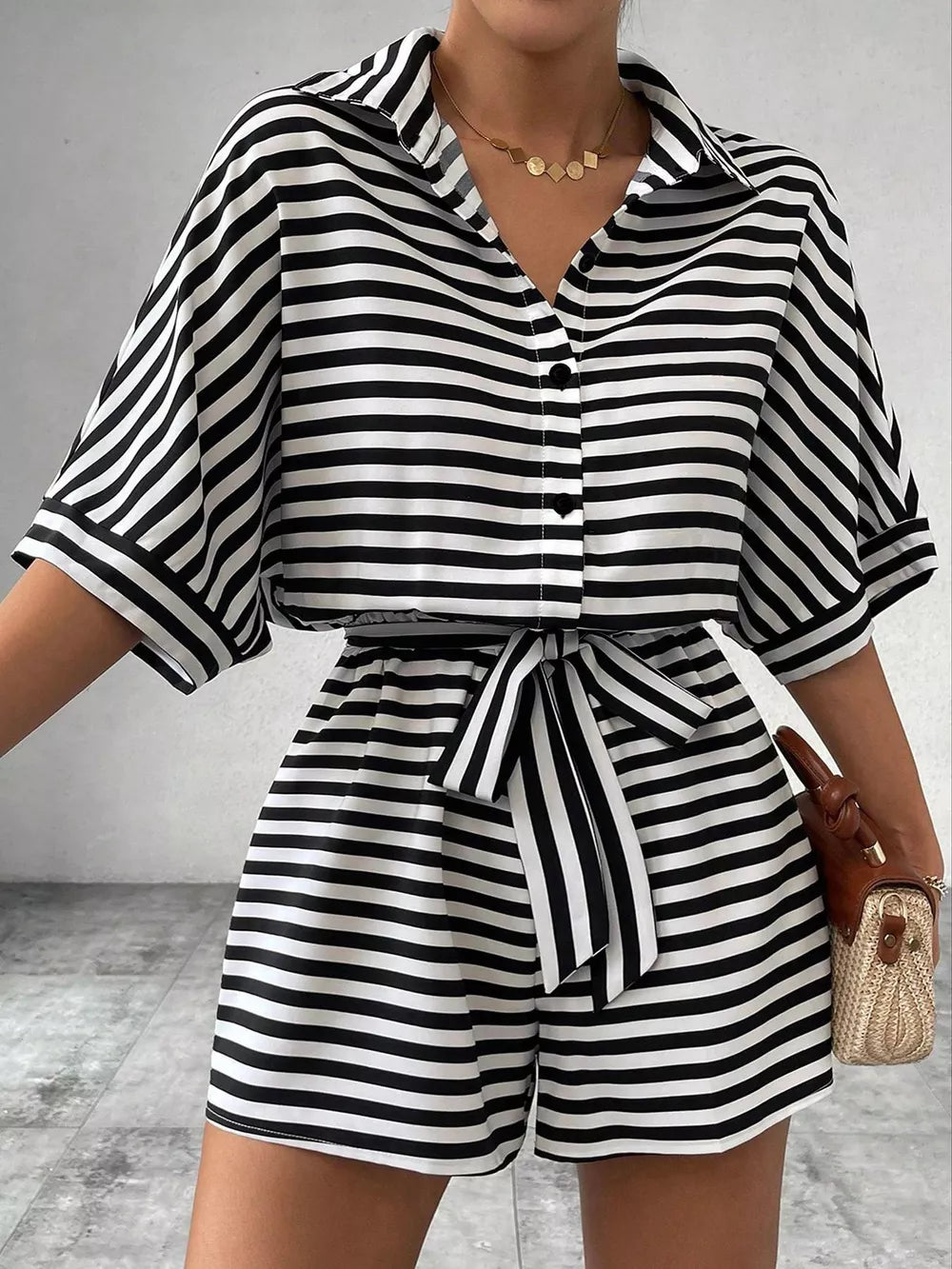 Black and white striped belted romper with collared button-front top and short sleeves.