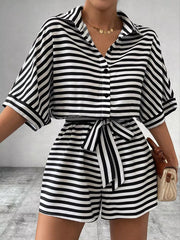 Black and white striped belted romper with collared button-front top and short sleeves.
