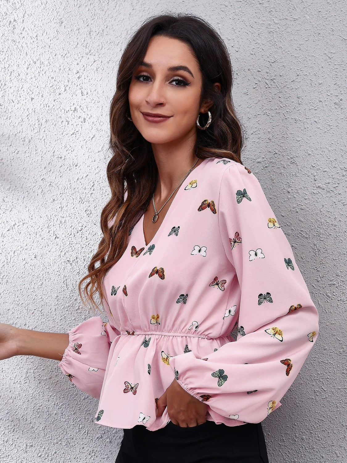 Blush pink peplum blouse with butterfly print, cinched waist, and balloon sleeves.