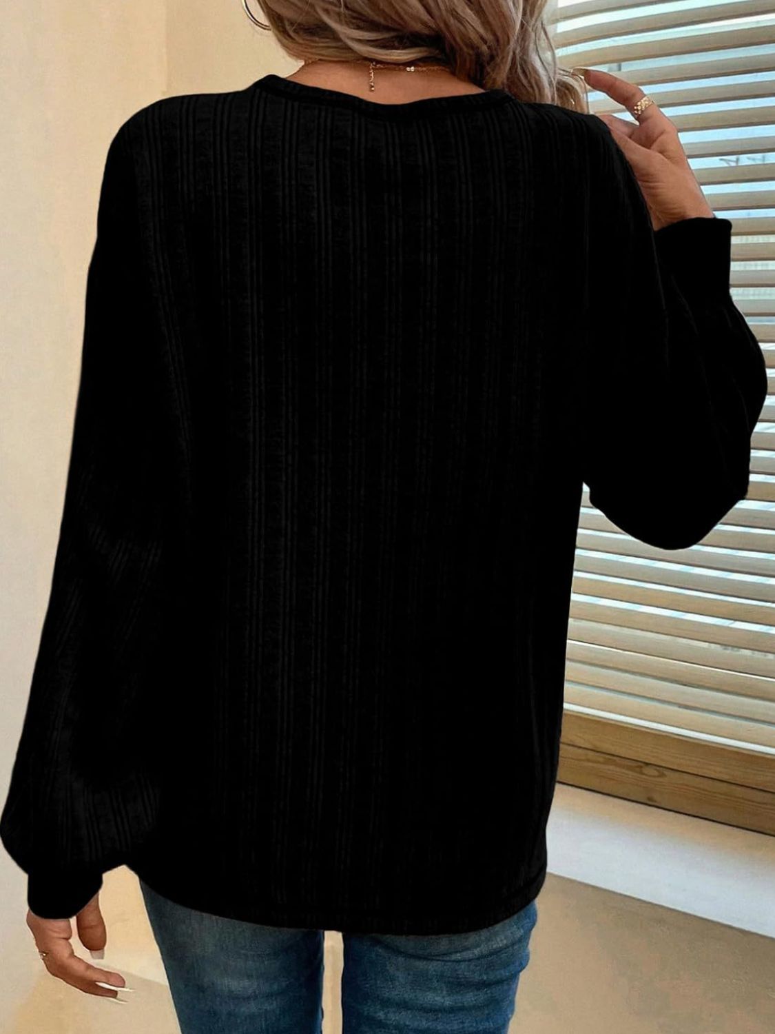 Black ribbed knit sweater with contrast stitching detail, long sleeves.