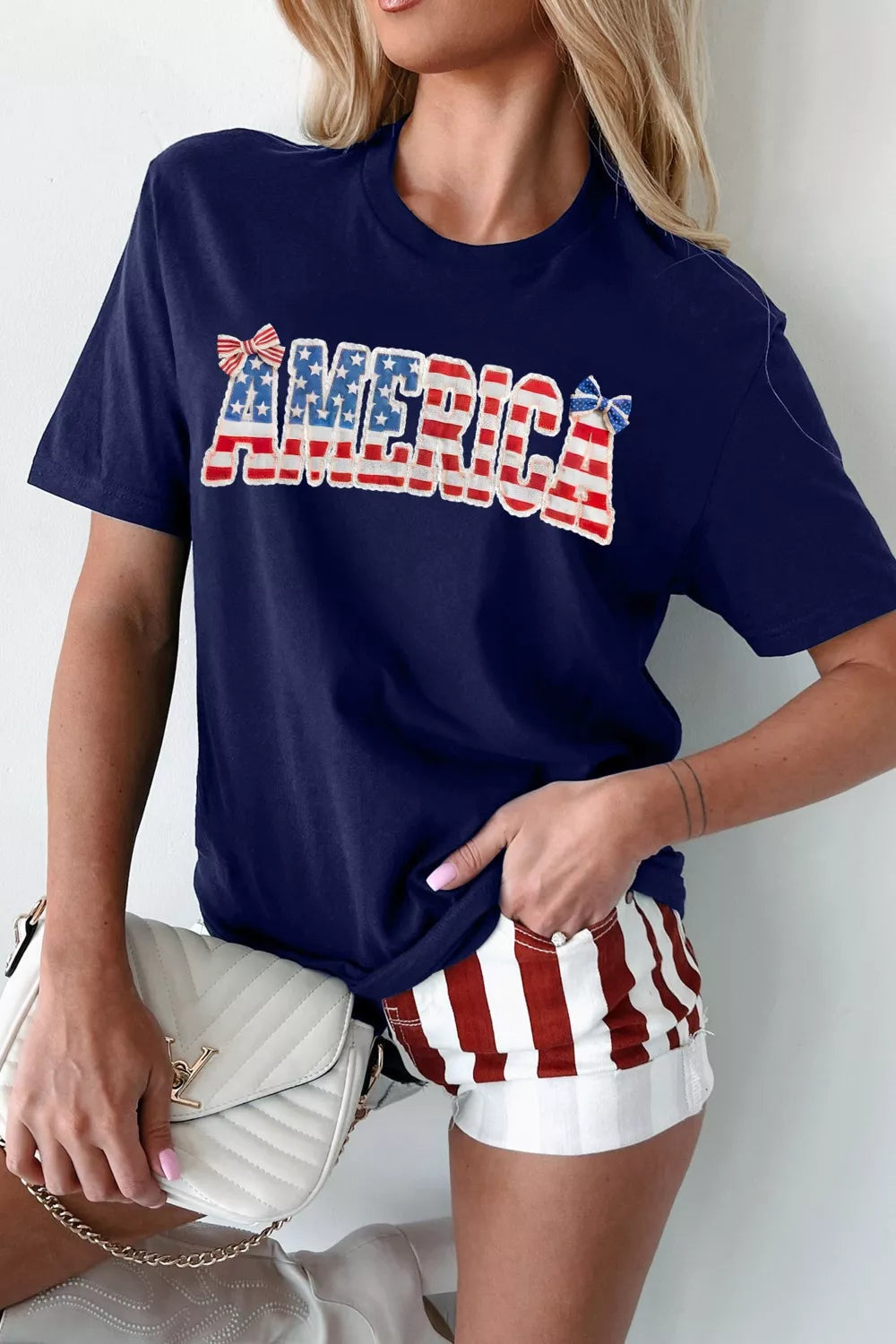 Navy patriotic graphic relaxed t-shirt with AMERICA text and bow details.