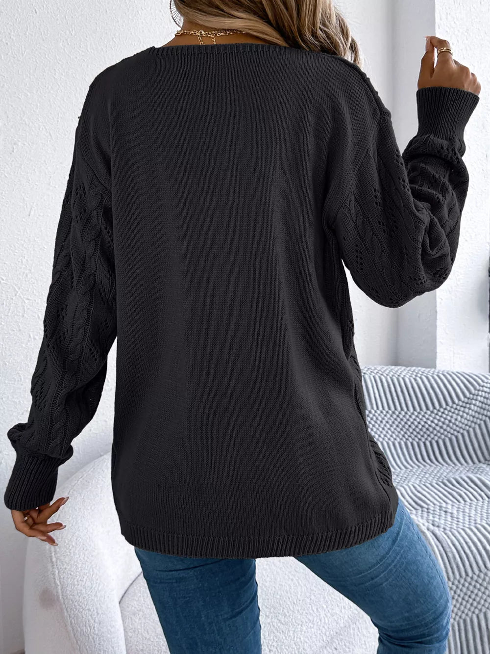 Black acrylic openwork cable knit cardigan with long sleeves.