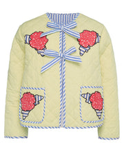 Pastel yellow quilted jacket with floral appliqué, blue striped trim, and bow closures.