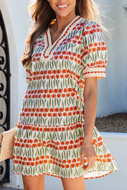 Cotton mini dress with red tulip print, V-neck, puff sleeves, and tiered skirt.