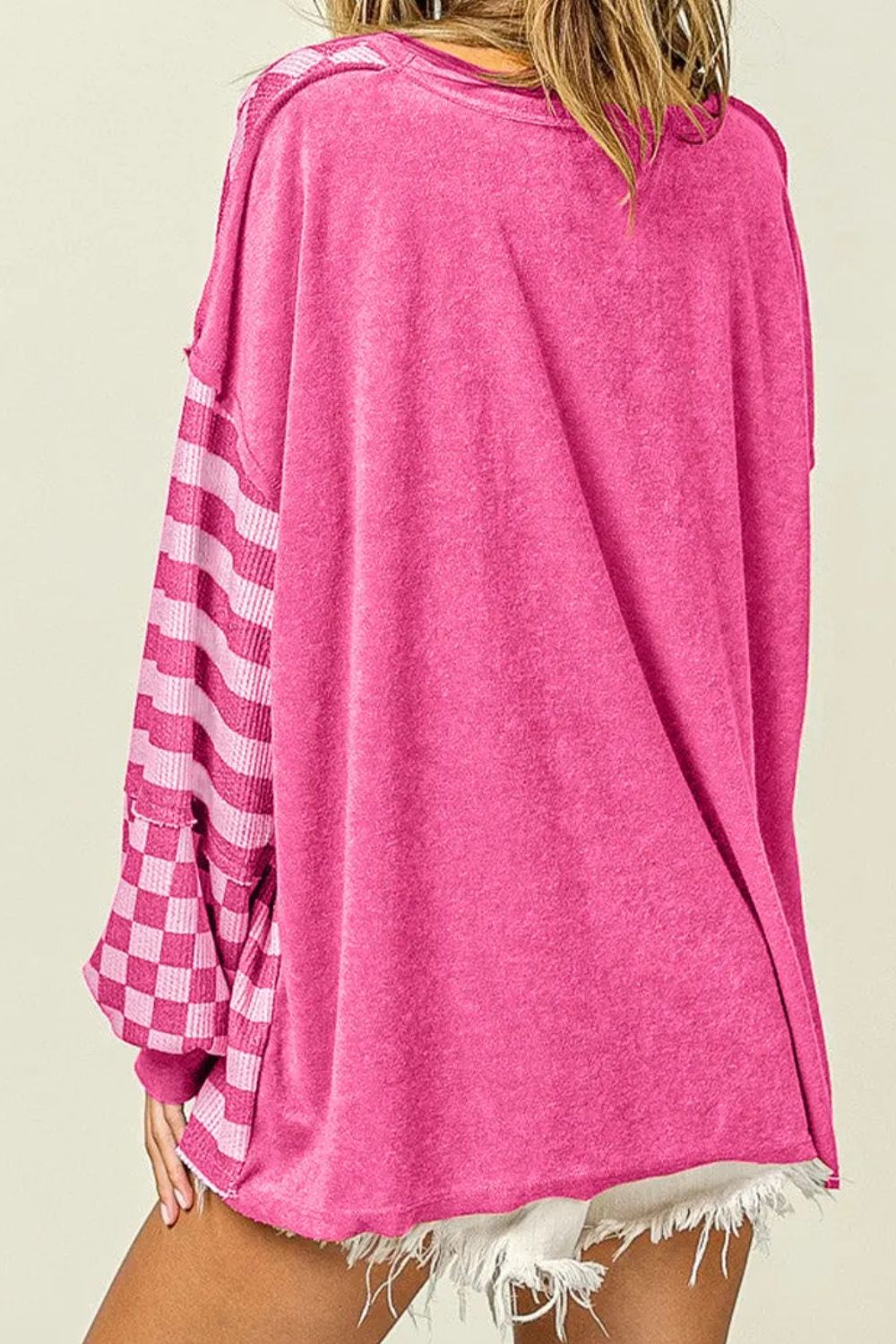 Hot Pink knit top with asymmetrical checkered and striped patchwork sleeves.