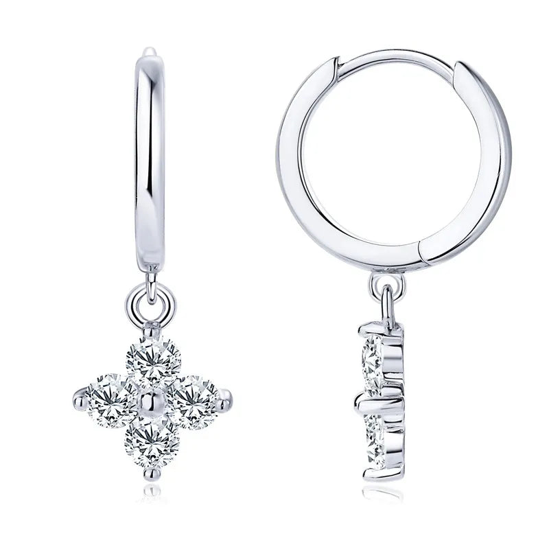 Silver huggie earrings with a dangling clover charm adorned with clear crystals.