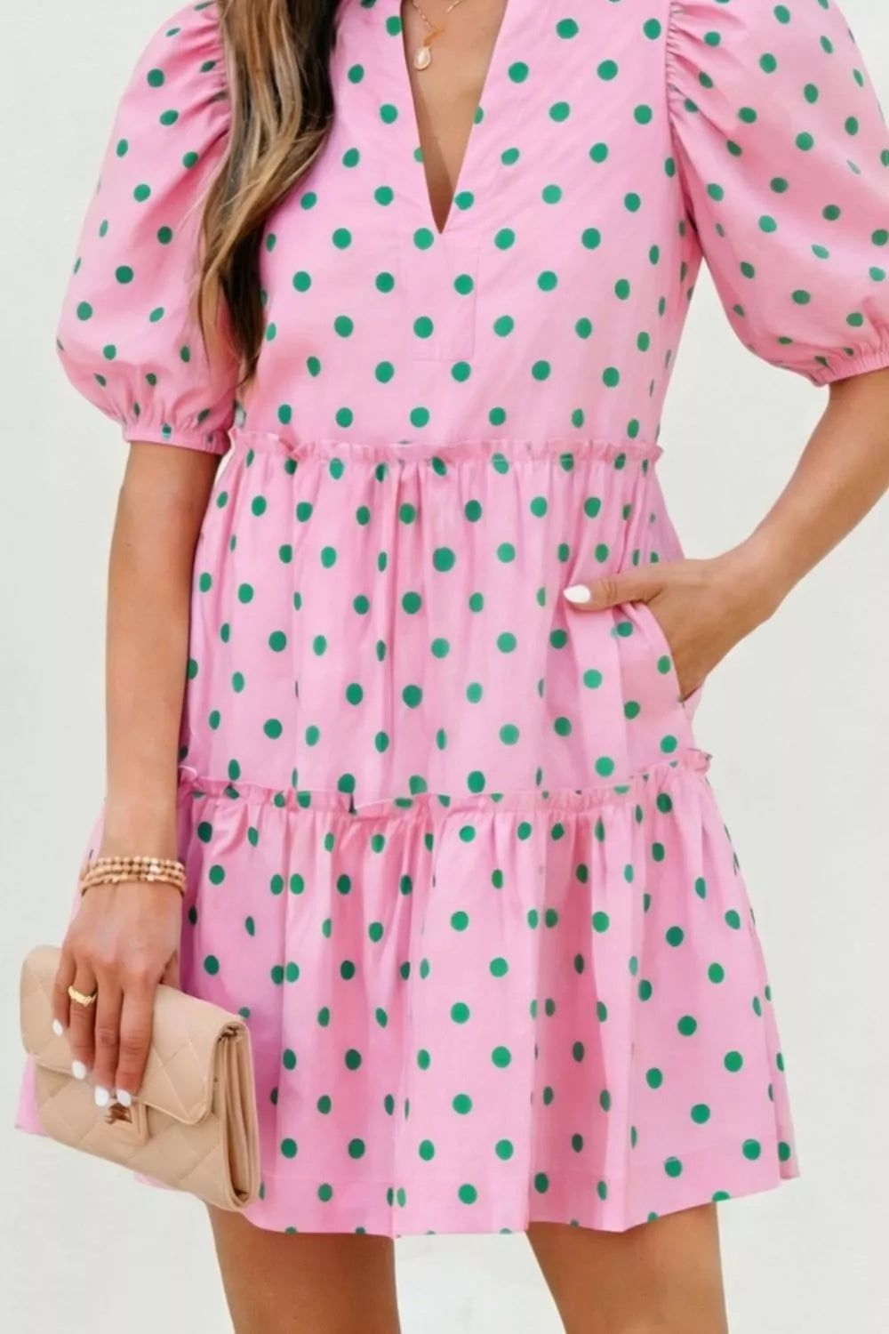 Pink polka dot tiered mini dress with puff sleeves and pockets.