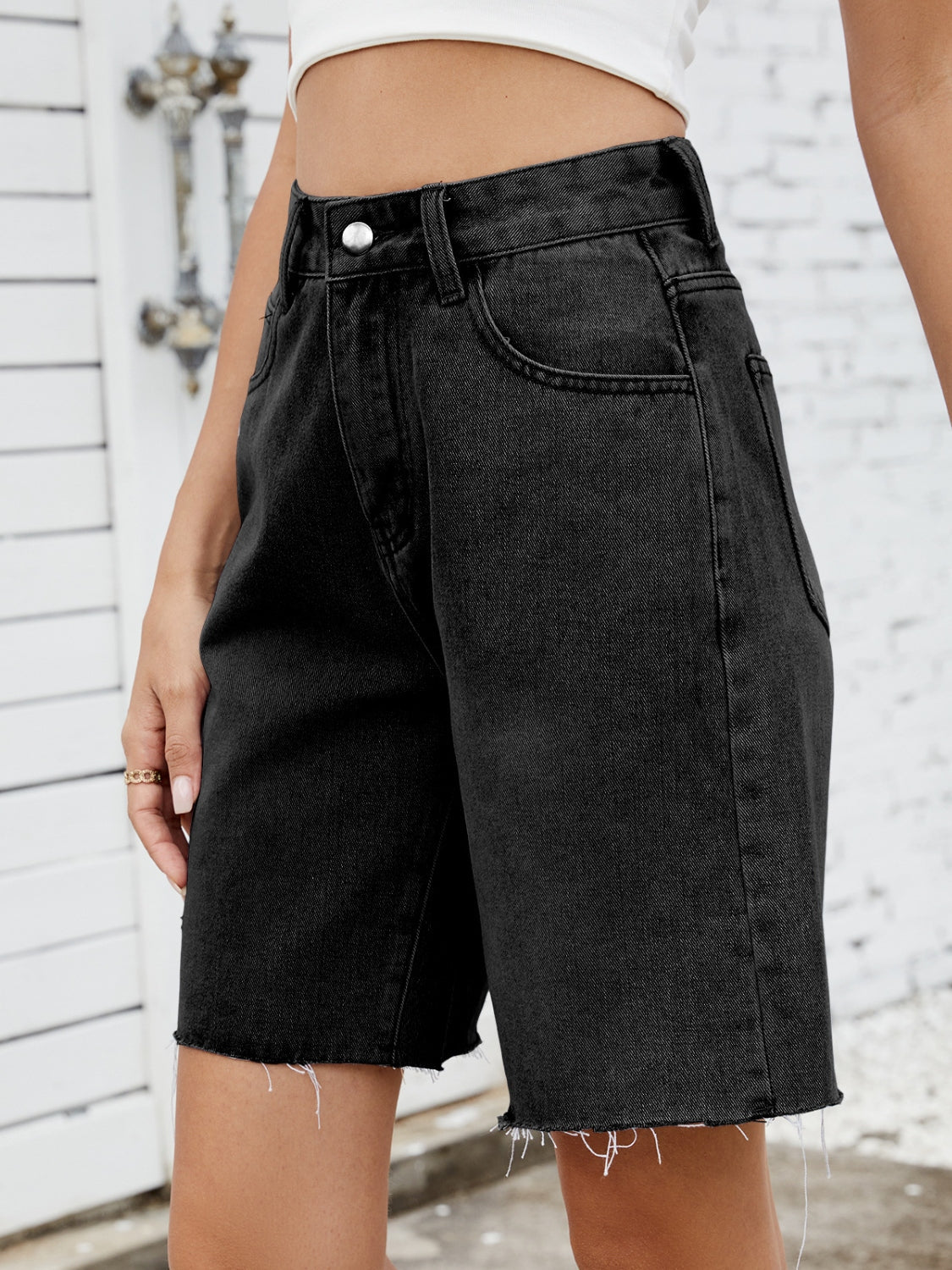 Black denim longline shorts with a raw hem and a casual fit.