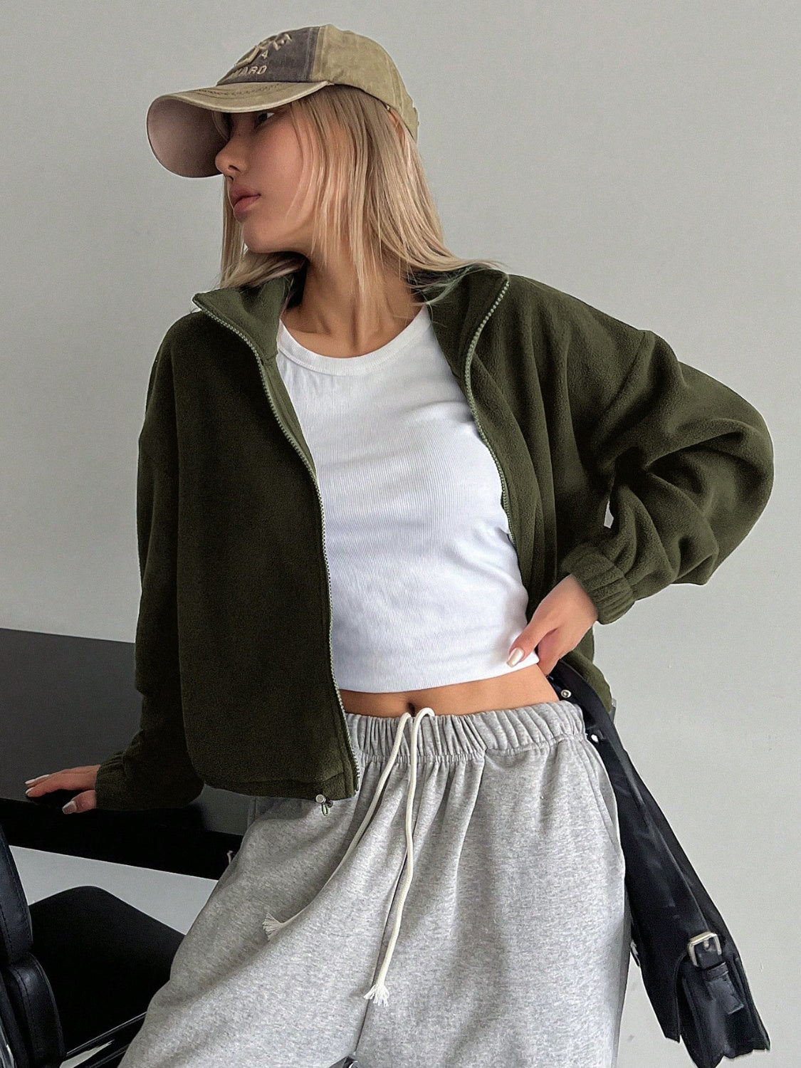 Olive fleece cropped jacket with funnel neck and zipper closure, styled with a white tank top.