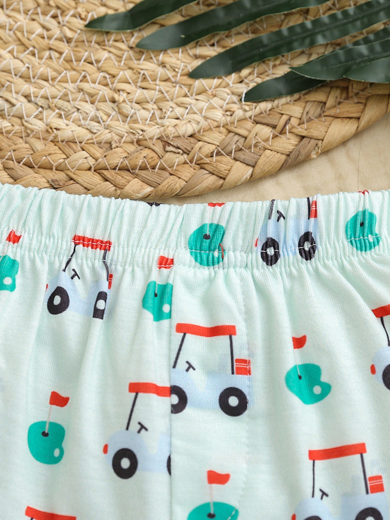 Baby shorts with elastic waistband and allover golf cart print in light green fabric.