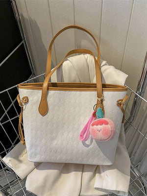 White diamond woven tote bag with tan straps and a pink peach charm.